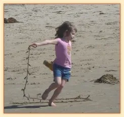 Girl running and drawing in the sand on a beach