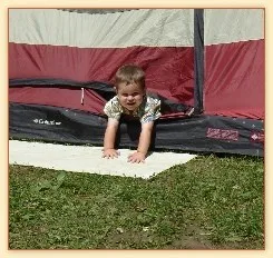 Toddler crawling out of a tent onto the grass