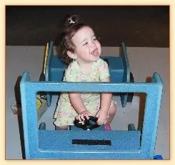 Toddler sitting in a toy car seat, laughing