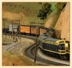 Model train running through a miniature canyon layout