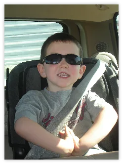 Boy in sunglasses buckled into a car seat
