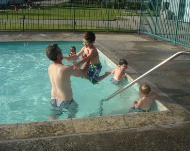 Dad playing with kids in an outdoor swimming pool