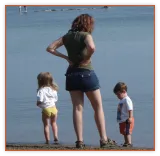 Mom watching two young children at the edge of a lake