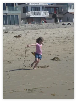 Girl drawing lines in the sand on a beach