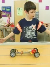 Boy racing a LEGO car at a children's museum