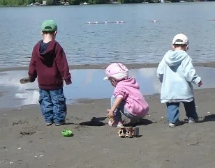Three toddlers playing on a lake beach