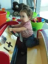 Toddler playing in a pretend car at a children's museum