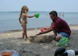Dad building a sandcastle with a little girl on the beach