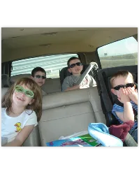 Kids smiling in the back seat of the car on a family road trip