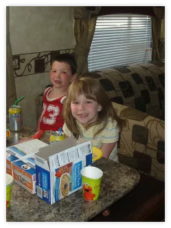 Two kids having breakfast at the table in an RV