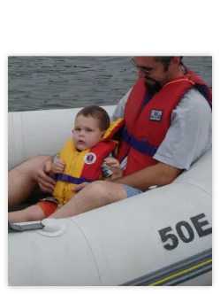 Toddler in a life jacket on an inflatable boat with a parent