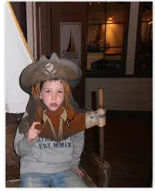 Boy dressed as a pirate posing with a wooden pirate cut-out